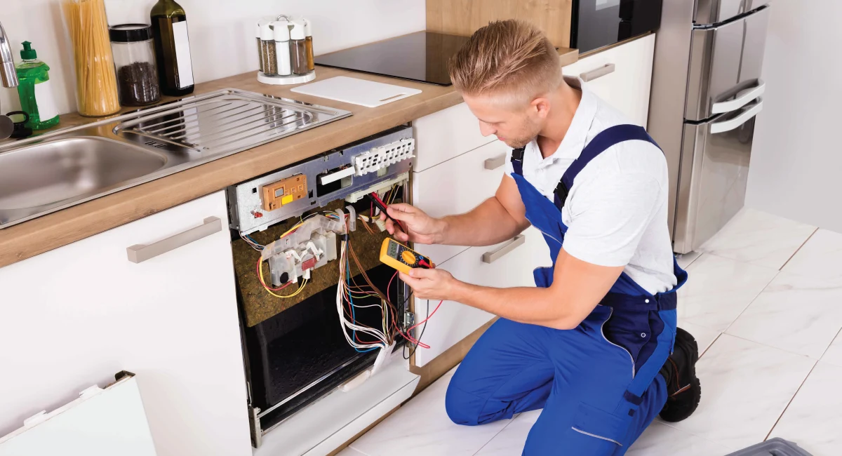 Technician testing the wiring and components of an open dishwasher