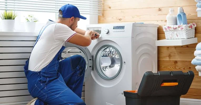 Appliance technician servicing a washing machine in a bright laundry room
